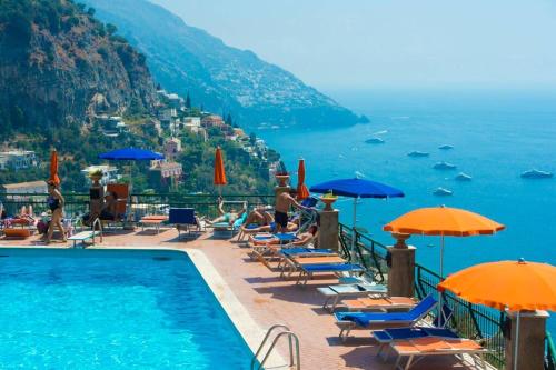 una piscina con sedie e ombrelloni accanto all'oceano di Villa Brayan - Positano Magical Sea View a Positano