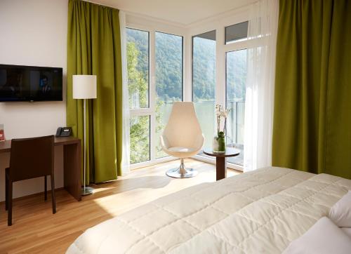 a bedroom with a bed and a desk and a window at Wesenufer Hotel & Seminarkultur an der Donau in Wesenufer