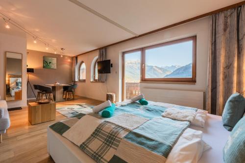 ein Schlafzimmer mit einem großen Bett und einem großen Fenster in der Unterkunft Alpin Resort Austria in Bichlbach