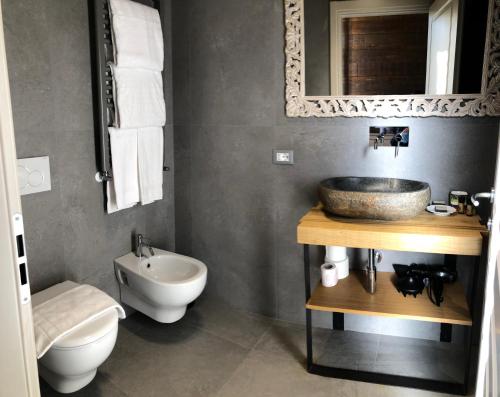 bagno con lavandino, servizi igienici e specchio di Chalet Lucca a Lucca