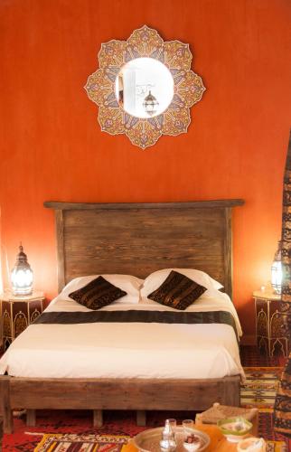 a bedroom with a bed and a mirror on the wall at Dar Sofar in Agdz