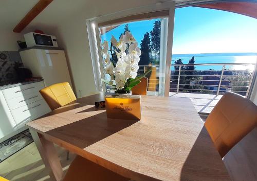 a dining room table with a vase of flowers on it at Red Rose Apartment in Portorož