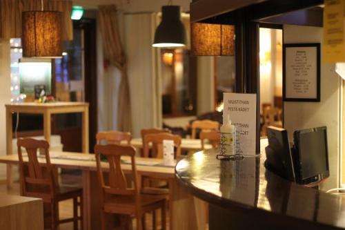 a restaurant with a bar with wooden chairs and a table at Hotelli Patruuna in Imatra
