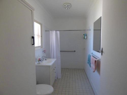 a white bathroom with a toilet and a sink at Parker st in Cootamundra