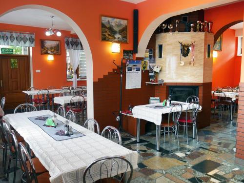 a restaurant with orange walls and tables and chairs at Dom Wczasowy Kazik in Maniowy