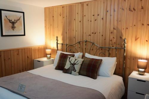 1 dormitorio con 1 cama con pared de madera en Waterfall Lodge - private waterfall and sauna en Killin