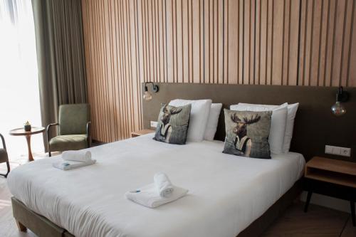 een hotelkamer met een groot bed met handdoeken erop bij Hotel de Boshoek in Voorthuizen