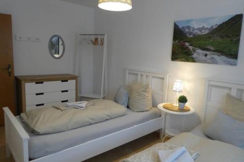 a white bedroom with a bed and a table at Allgäutraum Ferienwohnung Nr 10 in Kempten