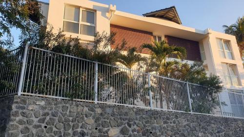 einen weißen Zaun vor einem Haus in der Unterkunft Appart Alexina, 2mn à pieds de la plage de BOUCAN-CANOT in Saint-Gilles-les-Bains