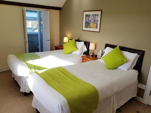 2 bedden in een hotelkamer met groene kussens bij Spacious 3-Bedroom 3-bathroom country cottage in Haverfordwest