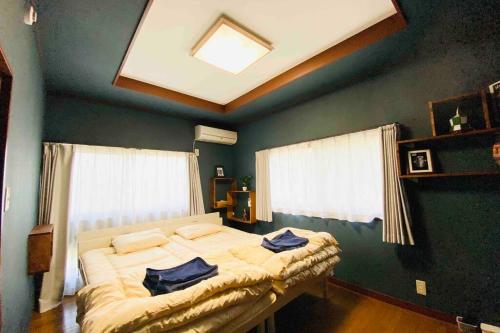 een slaapkamer met 2 bedden en een blauwe muur bij 48坪！道後温泉付近駐車場有り清潔さと設備の充実さが高評価 大切な家族仲間と広々とくつろげます in Matsuyama