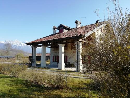an old building with a red roof on a field at Fienile Chiaramada in Belluno