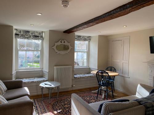 a living room with a couch and a table and two windows at Monmouth House Apartments, Lyme Regis Old Town, dog friendly in Lyme Regis