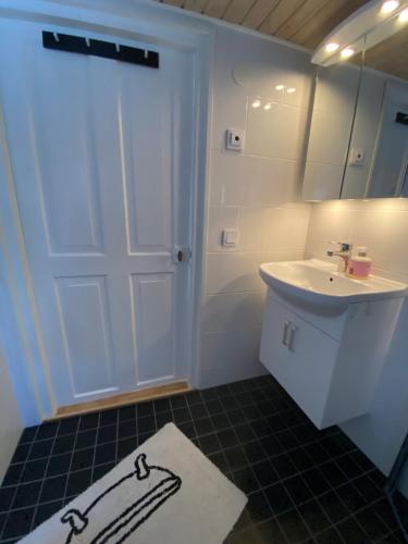 a bathroom with a white door and a sink at Stuga Romakloster in Romakloster
