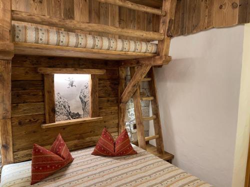 1 dormitorio con cama de madera y almohadas rojas. en Residence Lastè, en Moena