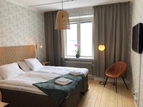 a bedroom with a bed and a chair and a window at Hotell & Bistro Rödesund in Karlsborg