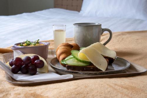 a plate of food with bread and fruit and a cup of milk at Hotell & Bistro Rödesund in Karlsborg