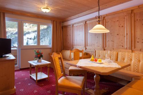 a dining room with a table and chairs and a television at Hotel Bergkristall in Silbertal