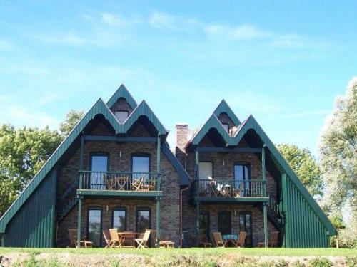 a large house with a green roof with tables and chairs at Zur-alten-Schmiede-II (Wohnung oben) in Boltenhagen