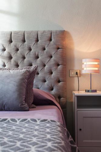 a bed with a large headboard and a table with a lamp at Antica Casa Balsari in Borgo Ticino