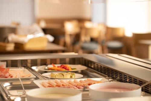 a buffet line with plates of food on dishes at OEKOTEL Hohenems in Hohenems