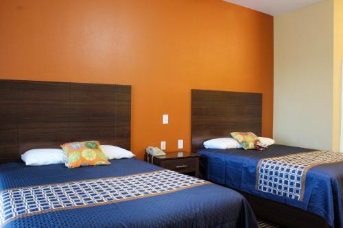 a room with two beds and an orange wall at Bungalows Hotel & Hotel Que at Lakeline Austin Cedar Park in Cedar Park