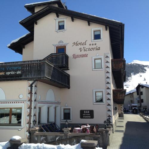 um grande edifício branco com uma varanda em Hotel Victoria em Livigno