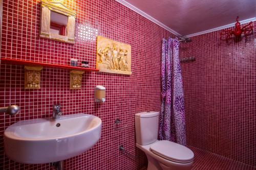 un bagno piastrellato rosso con lavandino e servizi igienici di Al 583 di Lindos a Líndos