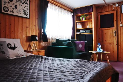a bedroom with a bed and a couch and a window at MSC Apartments Honeymoon in Zakopane