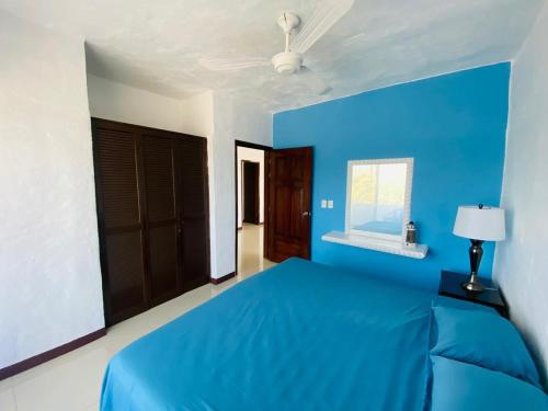 a blue bedroom with a bed and a window at Cocotero Manzanillo in Manzanillo