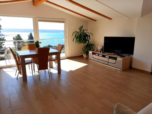 uma sala de estar com uma mesa de jantar e uma televisão em Red Rose Apartment em Portorož