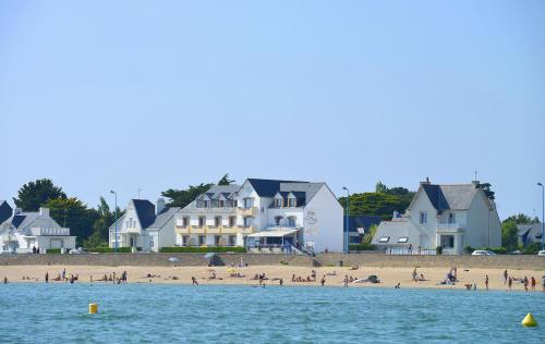 a group of people on a beach with houses at Hôtel De La Plage in Damgan