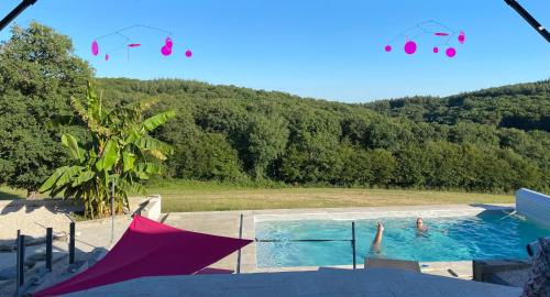 duas pessoas numa piscina com guarda-sóis em Maison d'hôtes à la Ferme Une Pause à la Guette em Uxeau