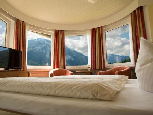 a bedroom with a bed and two chairs and windows at Haus Jäger Ferienwohnungen mit Indoor-Pool inkl. Chiemgaukarte in Ruhpolding