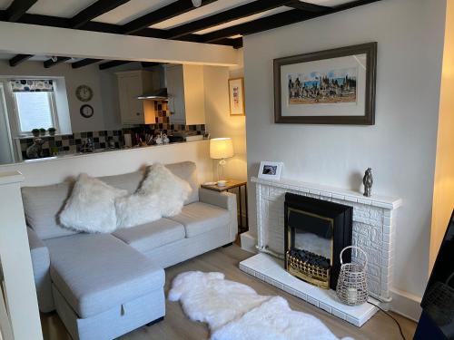 a living room with a white couch and a fireplace at The Nook Devon Square in Kingsbridge