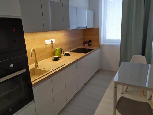 a kitchen with white cabinets and a sink and a table at Apartman TILL in Galanta