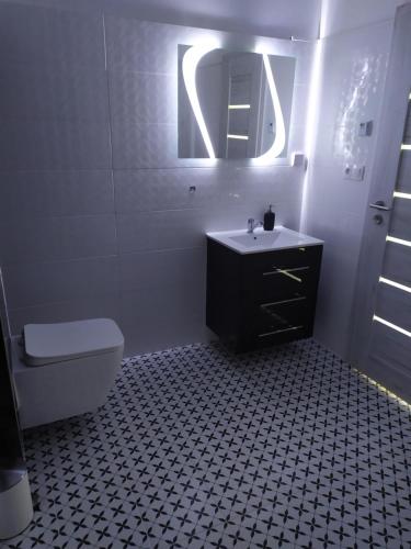 a bathroom with a sink and a toilet and a mirror at Apartman TILL in Galanta
