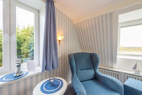a room with a chair and a table and windows at Inselhotel Arfsten in Wyk auf Föhr
