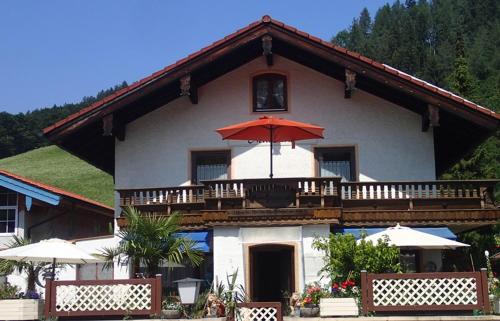 a house with a balcony with an umbrella at Haus Neuhäusl inkl. Chiemgaukarte in Ruhpolding