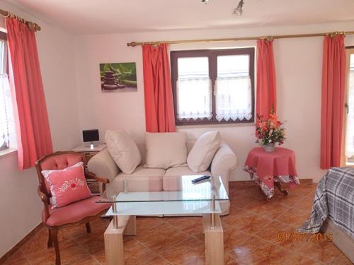 a living room with a white couch and red curtains at Haus Neuhäusl inkl. Chiemgaukarte in Ruhpolding