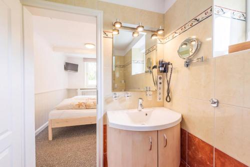 a bathroom with a sink and a mirror and a bed at Inselhotel Arfsten in Wyk auf Föhr