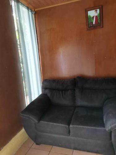 a black leather couch in a room with a window at Bijagua paradise Río Celeste in Bijagua