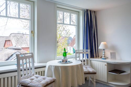a room with two chairs and a table and two windows at Inselhotel Arfsten in Wyk auf Föhr