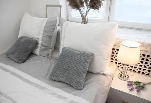 a bed with white pillows and a table with a lamp at Luxus Apartament Sea View Gdynia in Gdynia