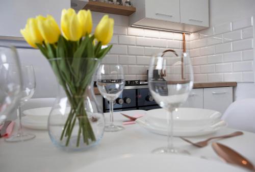 a table with three wine glasses and yellow tulips at Luxus Apartament Sea View Gdynia in Gdynia