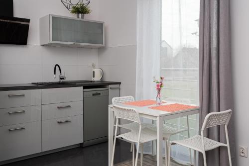 a white kitchen with a table and chairs at APARTAMENT Piątka in Jastrzębia Góra