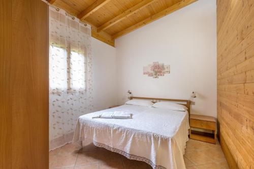 una camera con un letto bianco e una finestra di Agriturismo Alimini a Otranto a Otranto