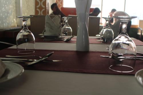 a wooden table with wine glasses and silverware on it at Hotel Blue Bird in Dhaka