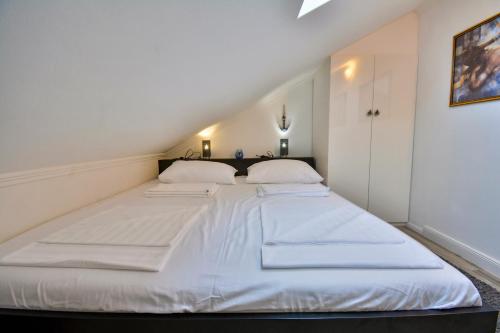 - un grand lit blanc avec 2 oreillers dans l'établissement Apartment 10 in Villa Petrac, à Rab