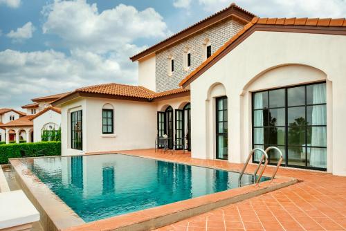 a swimming pool in front of a house at Mövenpick Resort Khao Yai in Ban Wang Sai